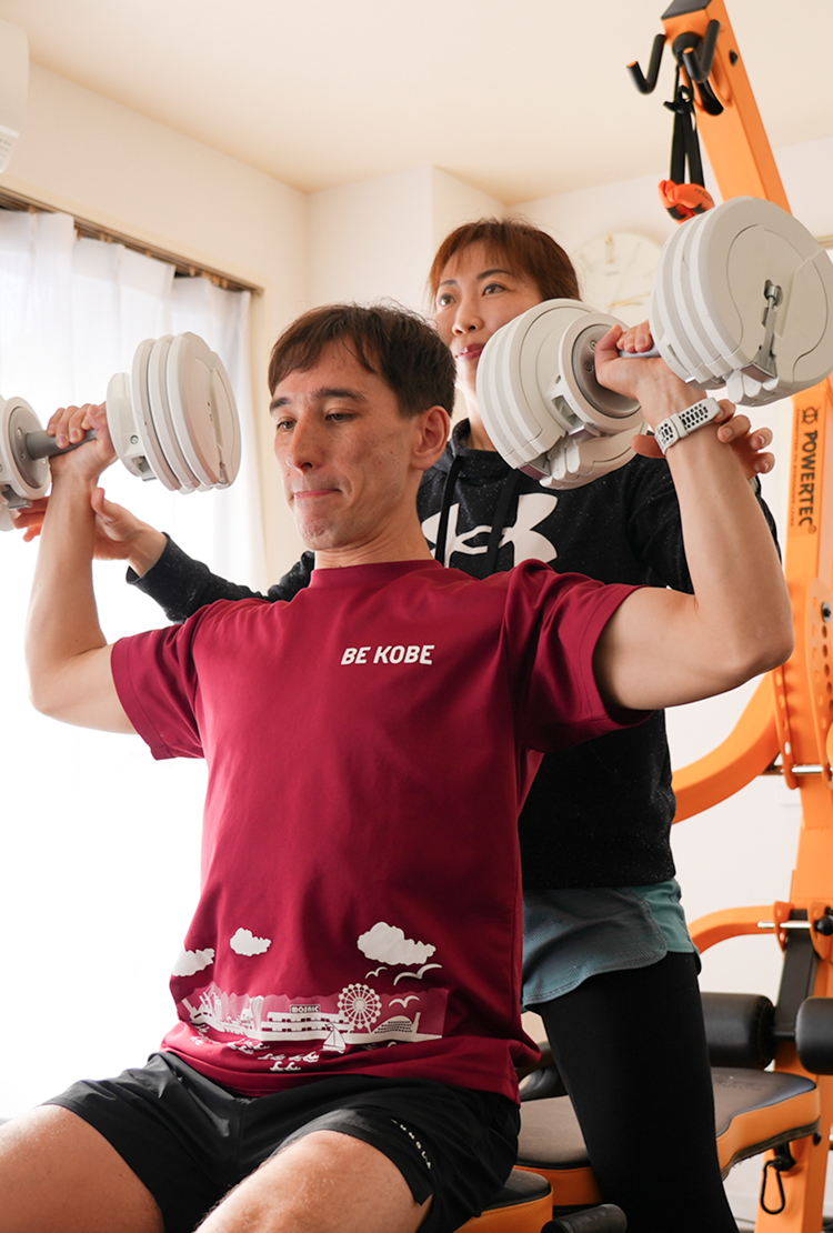 トレーナーとお客さんがショルダープレスをする